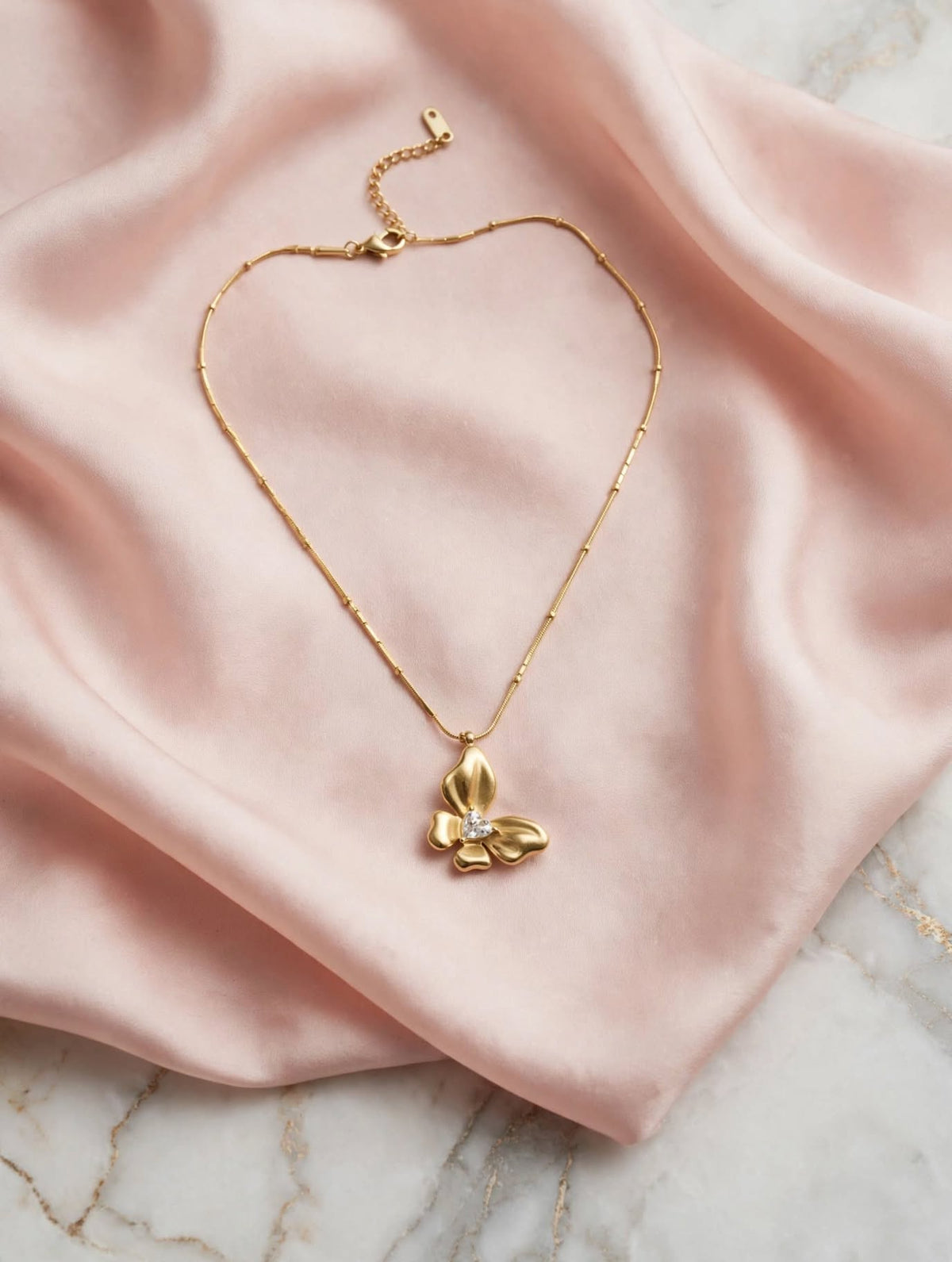 LUVORA butterfly pendant necklace gold on pink satin silk with marble background luxury lifestyle shot waterproof gold plated necklace
