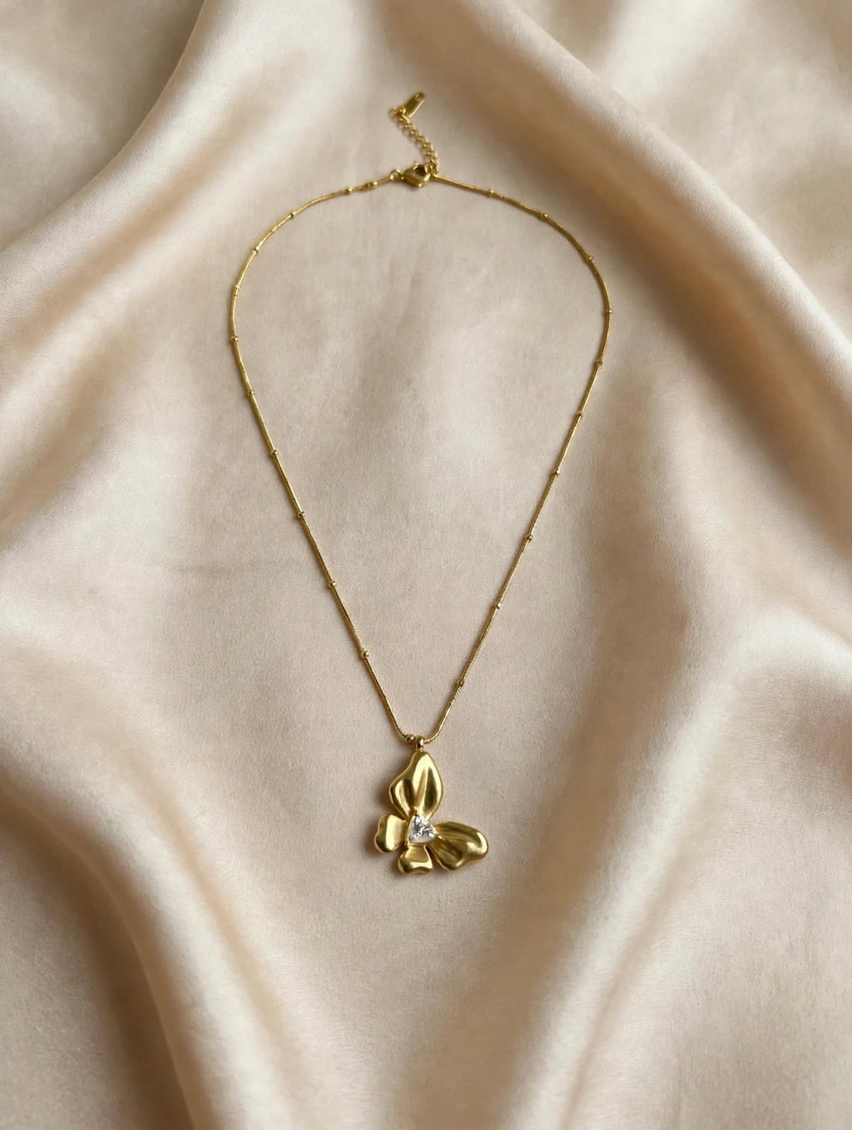Top view of LUVORA gold butterfly flower necklace with triangular zircon stone and beaded chain 