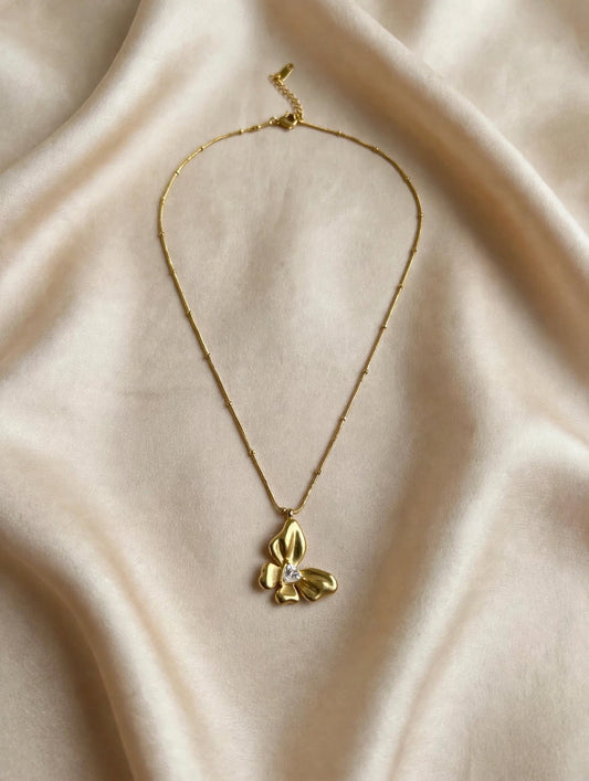 Top view of LUVORA gold butterfly flower necklace with triangular zircon stone and beaded chain 