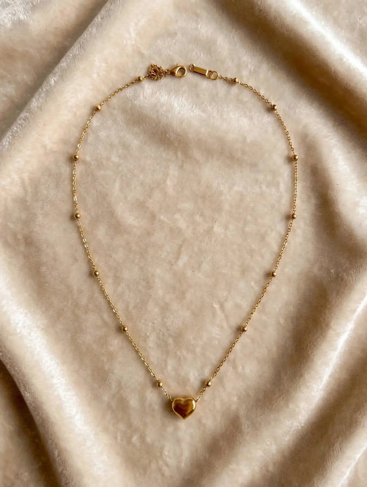 LUVORA gold heart beaded necklace on beige velvet